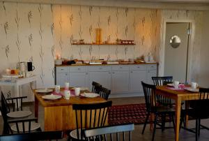 a dining room with a table and chairs and a kitchen at Nils Holgerssongården in Skurup