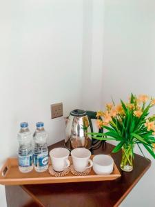 a wooden shelf with bowls and bottles of water and a plant at Tranquil Edge Villa in Haputale
