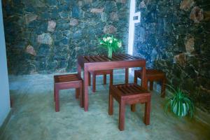 een houten tafel en banken met een vaas met bloemen erop bij Tranquil Edge Villa in Haputale