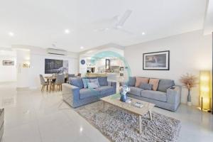 - un salon avec deux canapés bleus et une table dans l'établissement Zen Ocean Charm 3BR Luxury W/front Apt Pool + BBQ, à Darwin