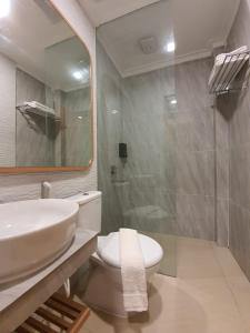 y baño con lavabo, aseo y ducha. en Muara Hotel Bukittinggi en Padangluar
