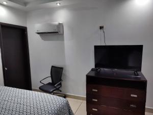 a bedroom with a bed and a dresser with a television at Hotel Don Quijote in Mexicali
