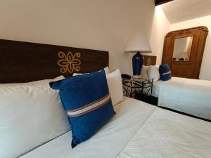 a hotel room with a bed with a blue pillow on it at Hotel Hacienda Monteverde San Miguel de Allende in San Miguel de Allende