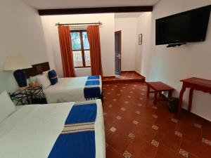 a hotel room with two beds and a flat screen tv at Hotel Hacienda Monteverde San Miguel de Allende in San Miguel de Allende