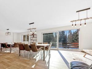 een eetkamer met een tafel en stoelen en een groot raam bij Chalet Familial Les Girolles aux portes d'Anzère in Arbaz