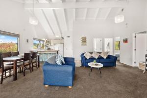 un soggiorno con 2 sedie blu e un tavolo di Waitahanui Lake House - Lake Taupo Holiday Home a Waitahanui