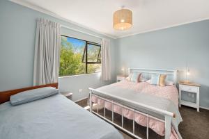 een slaapkamer met 2 bedden en een raam bij Waitahanui Lake House - Lake Taupo Holiday Home in Waitahanui