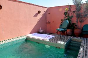 a swimming pool with a table and a chair next to a building at Riad Lila in Marrakesh