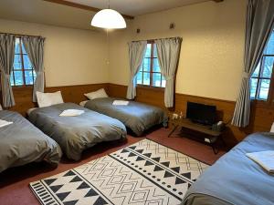 a room with three beds and a desk with a television at Shika Lodge in Iiyama +50 photos