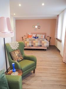 ein Wohnzimmer mit einem grünen Stuhl und einem Bett in der Unterkunft Tante ALMA's Mülheimer Hotel in Mülheim an der Ruhr