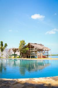 un complejo con piscina y techo de paja en The Blue Lagoon Resort Kalpitiya, en Kalpitiya