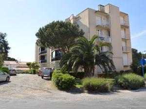 ein Gebäude mit Palmen und Autos auf einem Parkplatz in der Unterkunft Appartement Argelès-sur-Mer, 1 pièce, 2 personnes - FR-1-225-235 in Argelès-sur-Mer