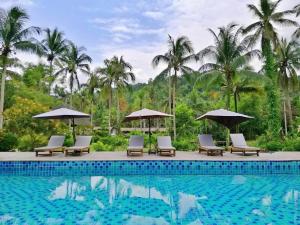 a pool at a resort with chairs and umbrellas at Jungle Koh Kood Resort in Ko Kood