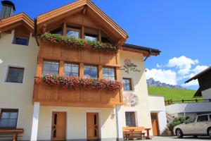 a building with a balcony with flowers on it at Ciasa La Rösa in Badia