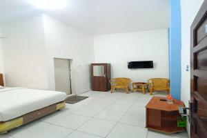 a bedroom with a bed and a tv on a wall at OYO 92207 Hotel Koperasi in Banda Aceh