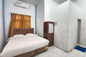 a small bedroom with a bed and a window at OYO 92207 Hotel Koperasi in Banda Aceh