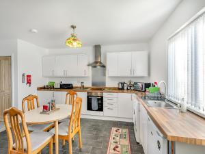 a kitchen with white cabinets and a table and chairs at The Bungalow in Denby