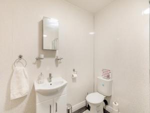 La salle de bains blanche est pourvue d'un lavabo et de toilettes. dans l'établissement The Bungalow, à Denby