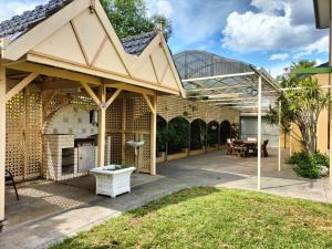 an outdoor patio with awning and a grill at 12 mins to Mel Airport-Good Wood House in St Albans