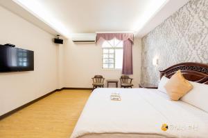 una camera con un grande letto e una televisione di Fu Bao Motel a Città di Hualien