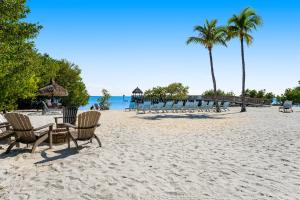 a beach with chairs and a table and palm trees at Nauti Hideaway, Unit #2314 in Tavernier