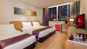ein Hotelzimmer mit 2 Betten und einem TV in der Unterkunft de King Boutique Hotel KLCC in Kuala Lumpur