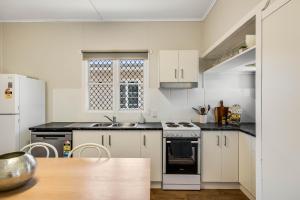 a kitchen with white appliances and a wooden table at Cute & Cheerful! Close to CBD & Gorgeous Parkland! in Toowoomba