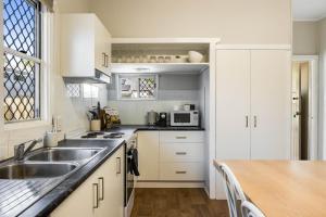 a kitchen with white cabinets and a sink at Cute & Cheerful! Close to CBD & Gorgeous Parkland! in Toowoomba