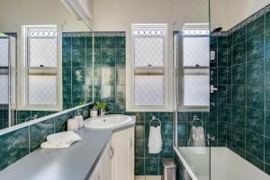La salle de bains est pourvue de carrelage vert, d'un lavabo et d'une douche. dans l'établissement Cute & Cheerful! Close to CBD & Gorgeous Parkland!, à Toowoomba
