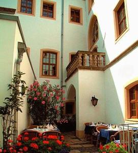 ゲルリッツにあるロマンティック ホテル トゥーフマッハーの中庭のテーブルと椅子付きの建物