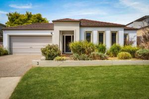 a house with a garage and a green lawn at Shallow Water Retreat in Cowes