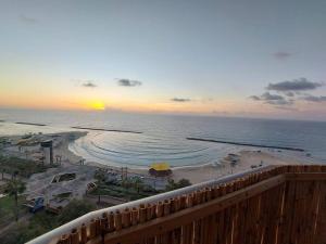 uma vista para uma praia com o pôr-do-sol sobre o oceano em apartment with sea view- itallian jaccuzi em Netanya