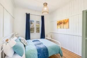 a bedroom with a bed with blue and white pillows at Cheerful, Cosy Cottage - Near Rose Garden! in Toowoomba