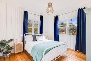 1 dormitorio con 1 cama con cortinas azules en Cheerful, Cosy Cottage - Near Rose Garden!, en Toowoomba