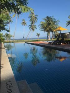a swimming pool with palm trees and the ocean at DEEPSPACE cabin on Quiet Beach in Ko Lanta