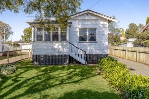 a tiny house in a yard with a fence at Cheerful, Cosy Cottage - Near Rose Garden! in Toowoomba