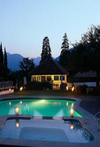 una piscina por la noche con una casa en el fondo en Pension Riedingerhof en Merano