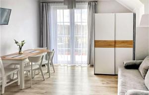 a dining room with a table and a white refrigerator at Gorgeous Apartment In Karwia With Kitchen in Karwia