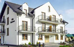 Casa blanca con balcones y valla en Gorgeous Apartment In Karwia With Kitchen, en Karwia