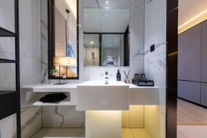 a bathroom with a white sink and a mirror at Ausotel by Argyle Baiyun Airport Renhe MTR in Guangzhou