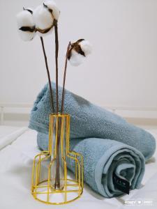 a vase with two flowers in it next to towels at Hanns&FreeWiFi&Washer&Parking &Pool&Sauna&Sunshine Comfort Homstay2 in Sibu