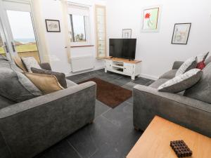 茅根海岸的住宿－White Lodge Apartment，客厅配有2张沙发和1台平面电视
