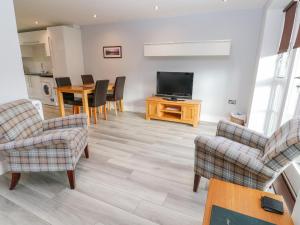 a living room with chairs and a television and a table at 19 Bay Retreat Villas in St Merryn