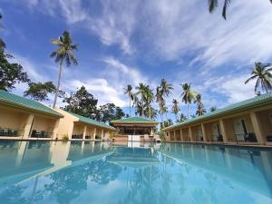 a swimming pool in front of a resort with palm trees at Coco Cabana Apartelle in Panglao Island