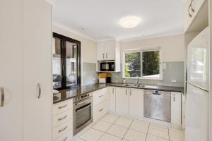 a kitchen with white cabinets and stainless steel appliances at Perfect CDB & Parkland Fringe! in Toowoomba