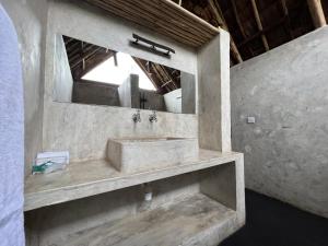 Baño de piedra con lavabo y espejo en The Jungle Pearl Resort, en Mto wa Mbu