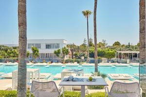 een zwembad met een tafel en stoelen en palmbomen bij So White Club Resort in Ayia Napa
