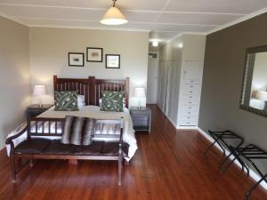 ein Schlafzimmer mit einem Bett und einer Bank in einem Zimmer in der Unterkunft The Ranch House at African Safari Lodge in Grahamstown