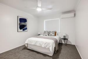 a white bedroom with a bed and a ceiling fan at Eastside Haven - Central & Convenient! in Toowoomba