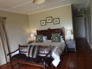 ein Schlafzimmer mit einem Bett und einer Bank mit Kissen in der Unterkunft The Ranch House at African Safari Lodge in Grahamstown